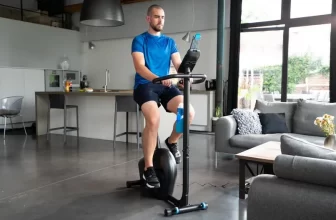 Un homme sur un vélo d'appartement pas cher Domyos dans un intérieur moderne.